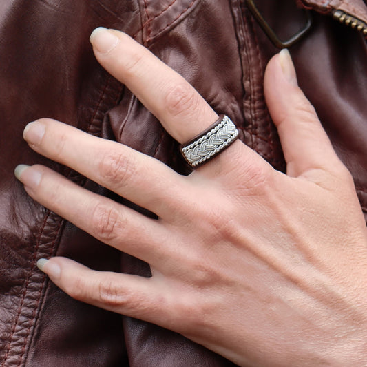 Sami ring in dark brown leather with pewter braids, on a finger