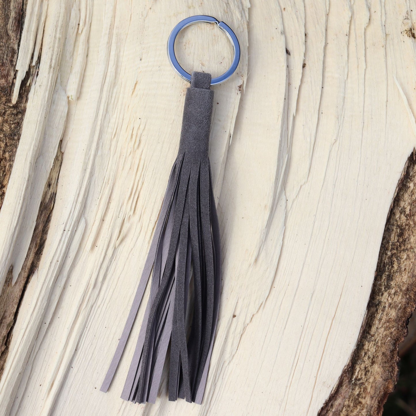 Handcrafted tassel in soft ardoise reindeer suede shown on wood