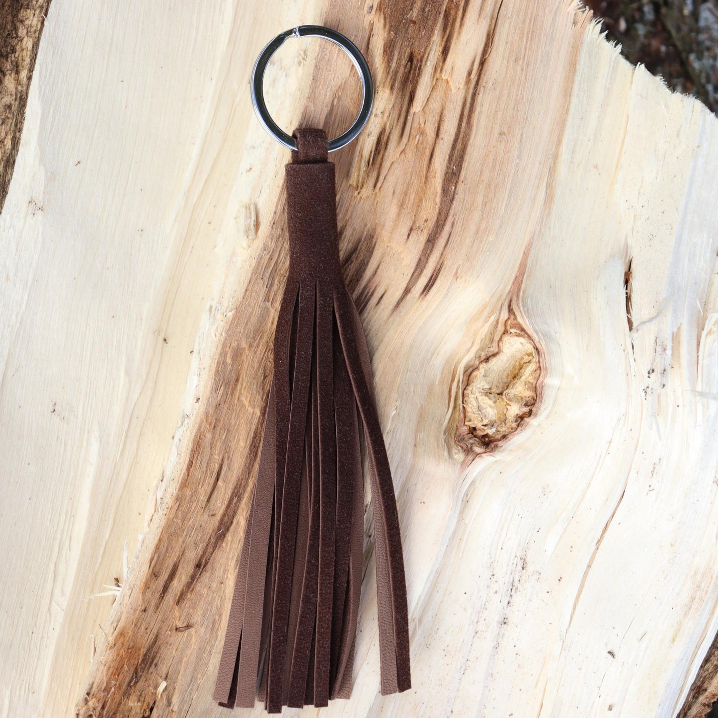 Handcrafted tassel in soft dark brown reindeer suede shown on wood