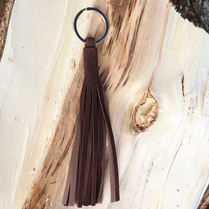 Handcrafted tassel in soft dark brown reindeer suede shown on wood