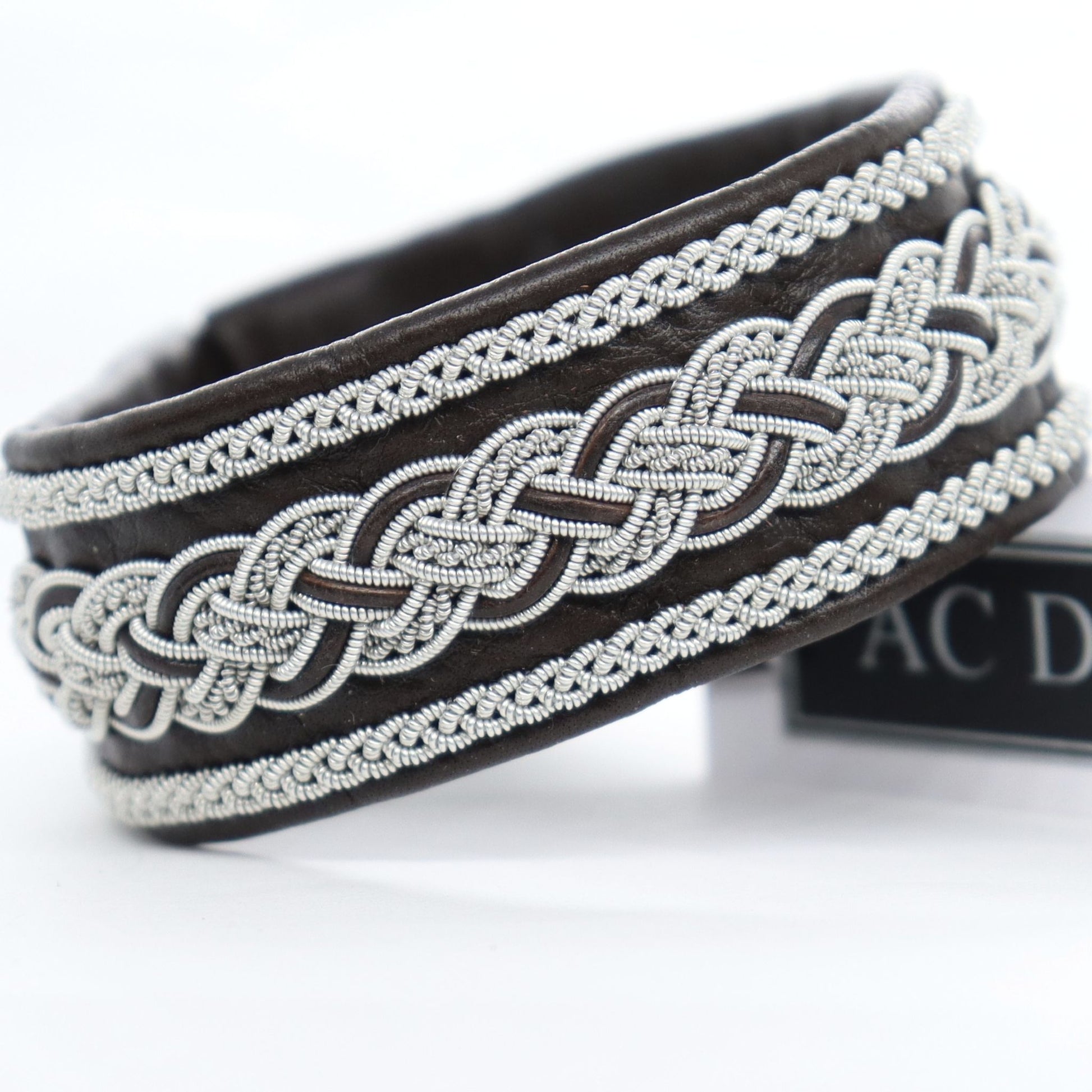 Wide dark brown Sami bracelet handcrafted in leather with pewter braiding. 