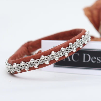 Close-up of a slim Sami bracelet with braided pewter thread and silver beads