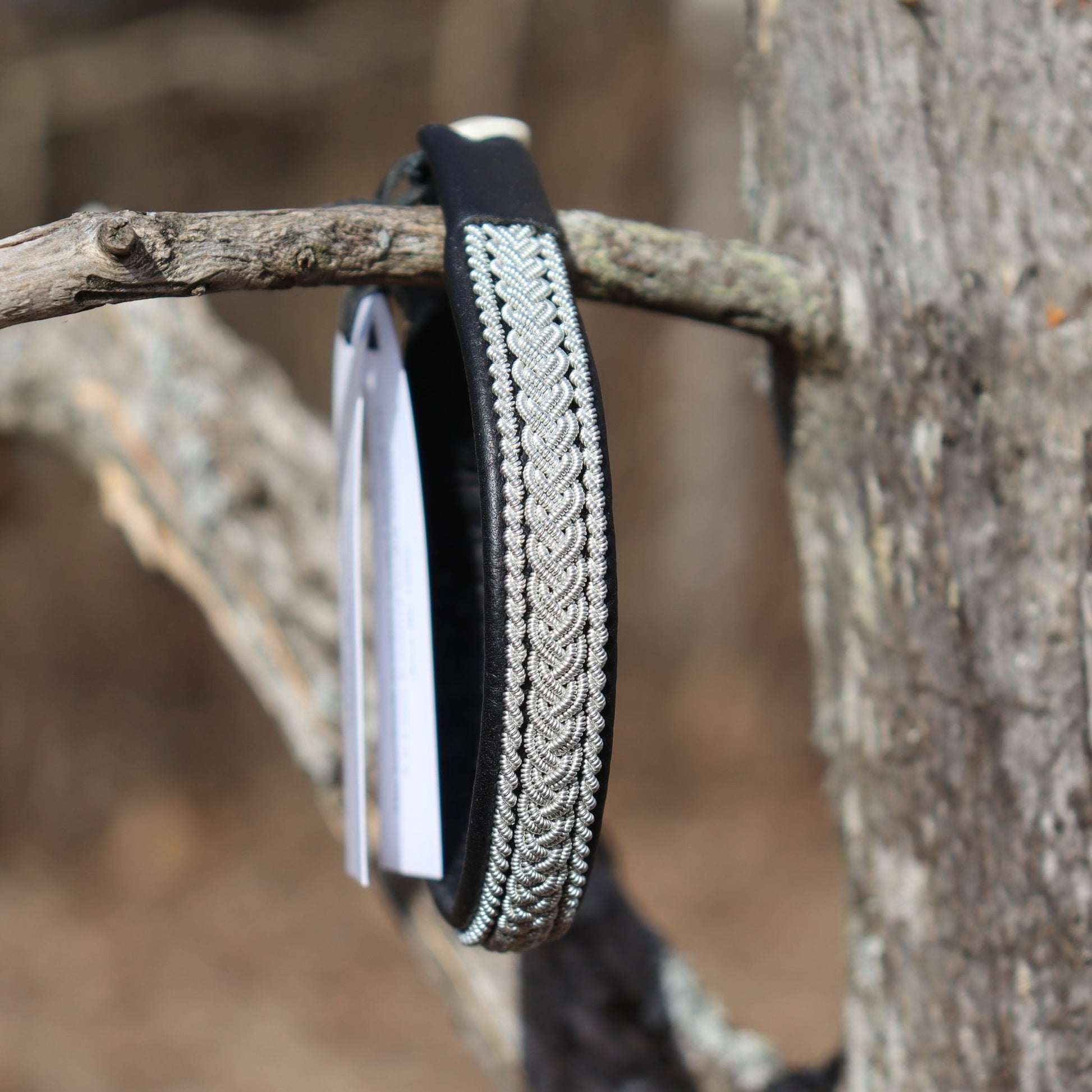 Handcrafted Sami leather bracelet with braided pewter thread photographed outdoors