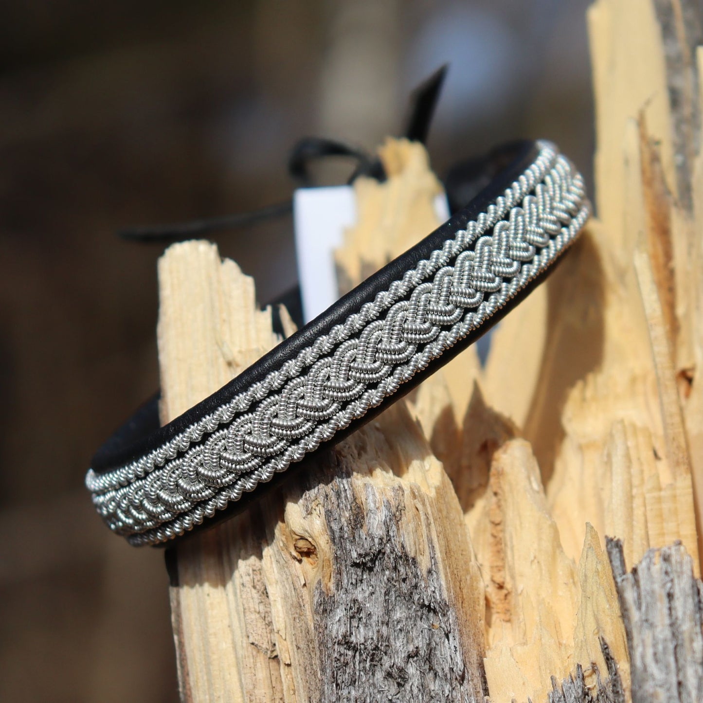 Handcrafted Sami leather bracelet with braided pewter thread shown on wood