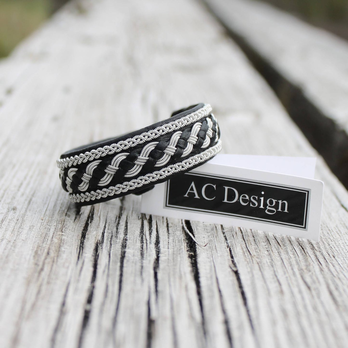Swedish bracelet in black leather and pewter wire braids shown on wood