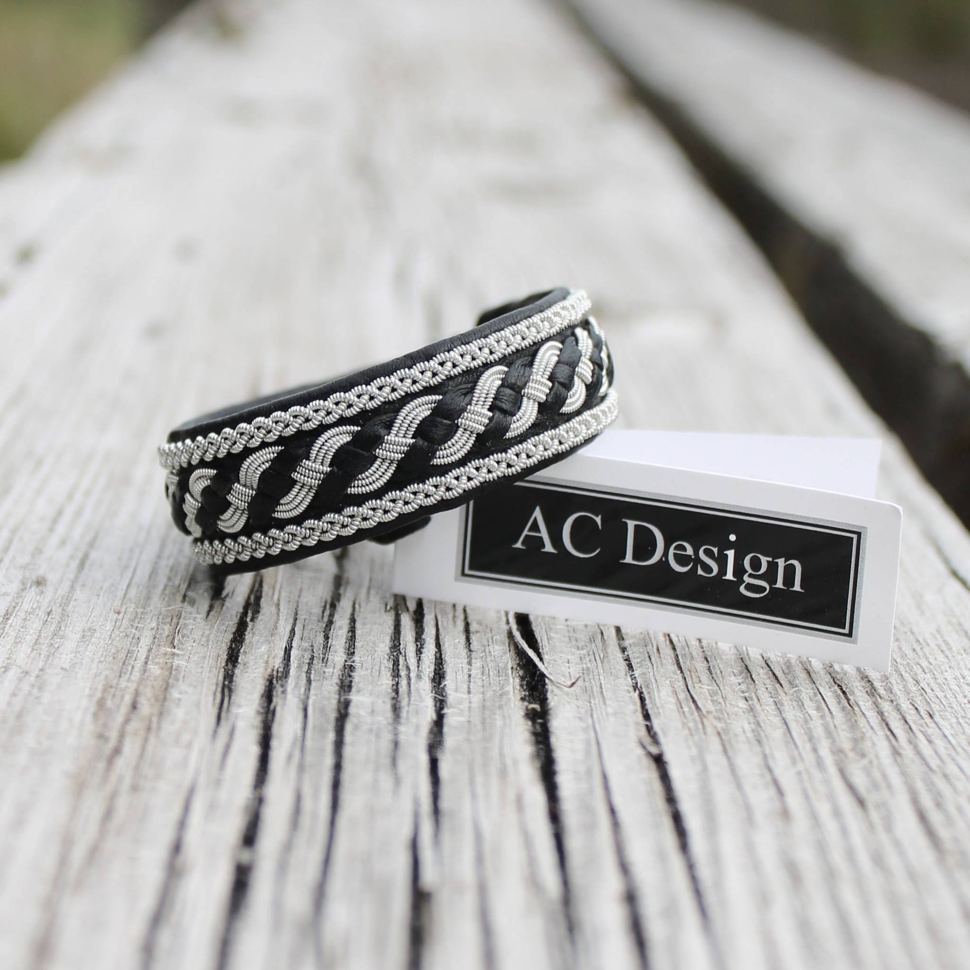 Swedish bracelet in black leather and pewter wire braids shown on wood
