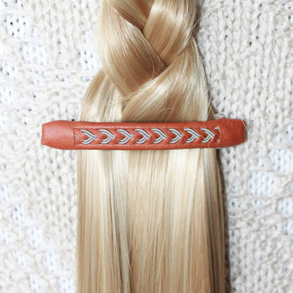 Handmade Sami leather and pewter hair clip used to secure a braid