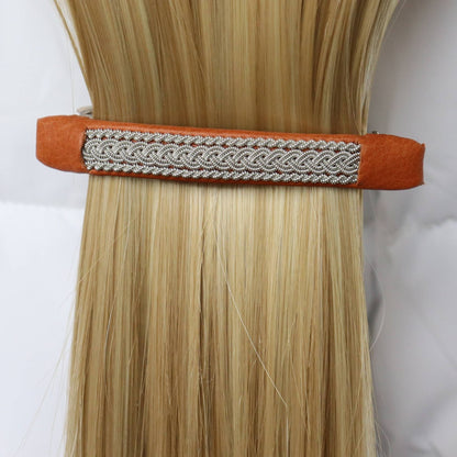 Swedish handcrafted Sámi hair barrette in natural brown leather with pewter braid, worn in hair