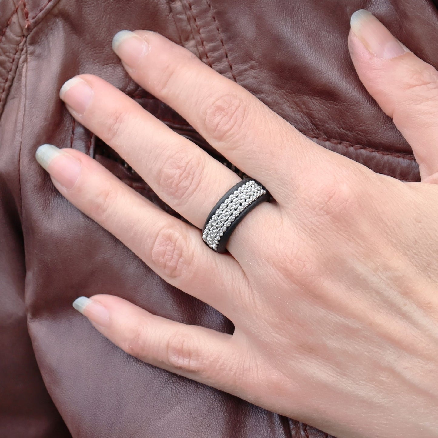Sami ring in black leather with pewter braids, worn on finger