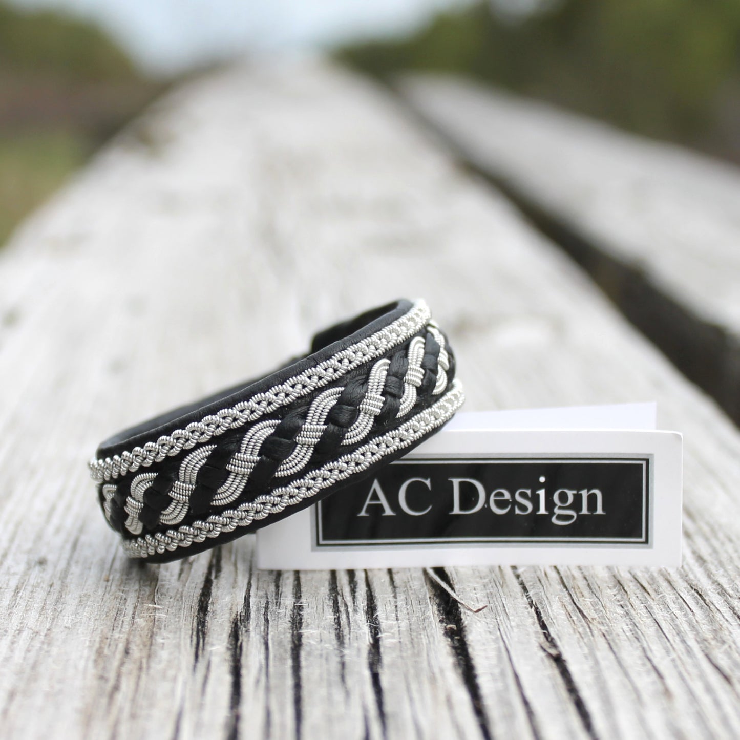 Black sami bracelet in leather and pewter wire braids, on wood deck